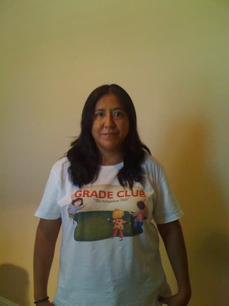 Woman with long dark hair wearing a white t-shirt with a 'GRADE CLUB' graphic.